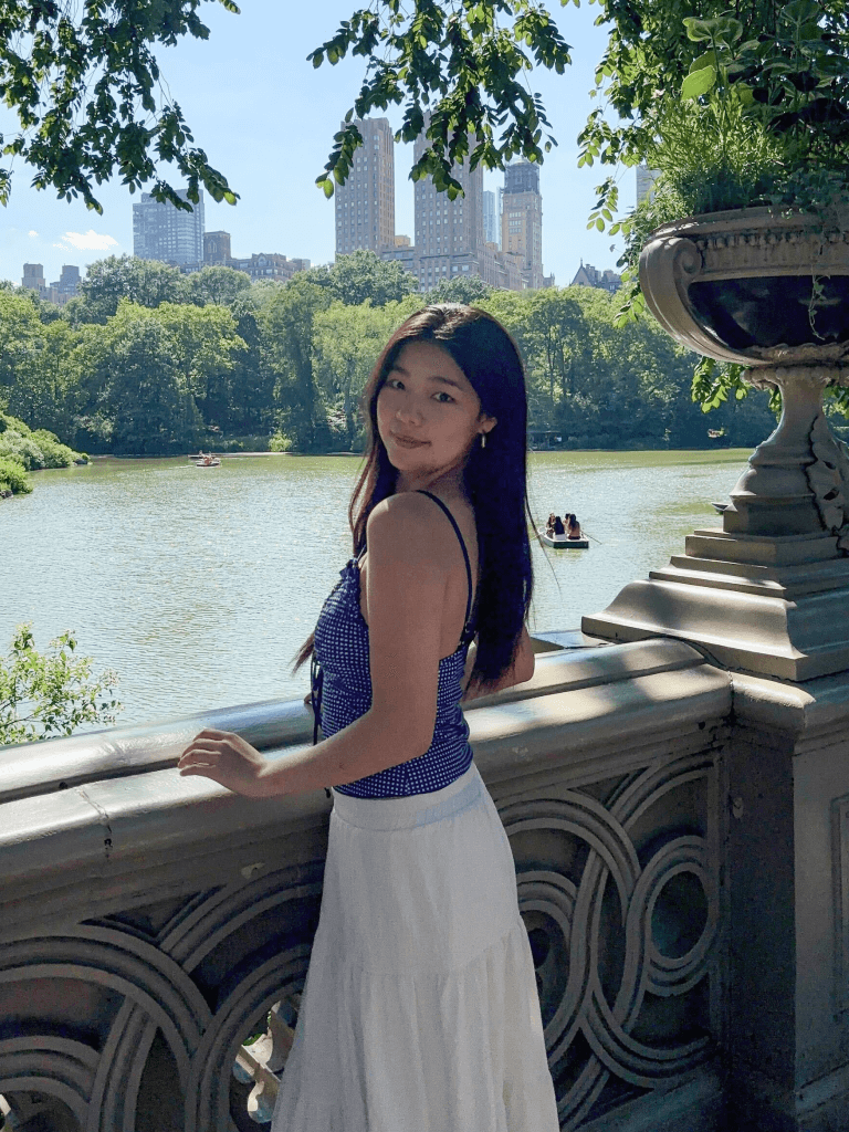 Sarah standing outdoors with a city skyline behind her